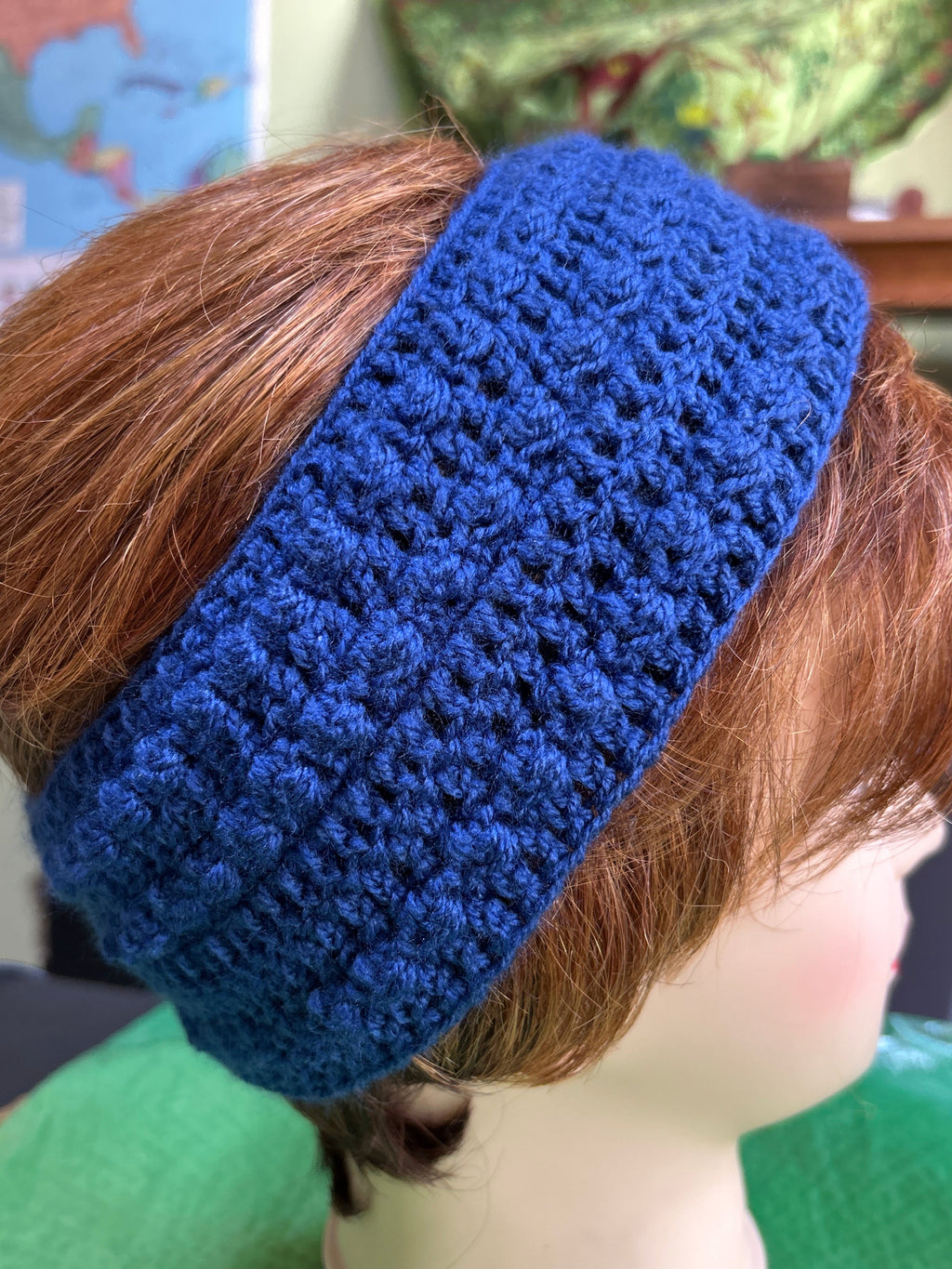 Blue knitted headband on a mannequin head with a blurred background