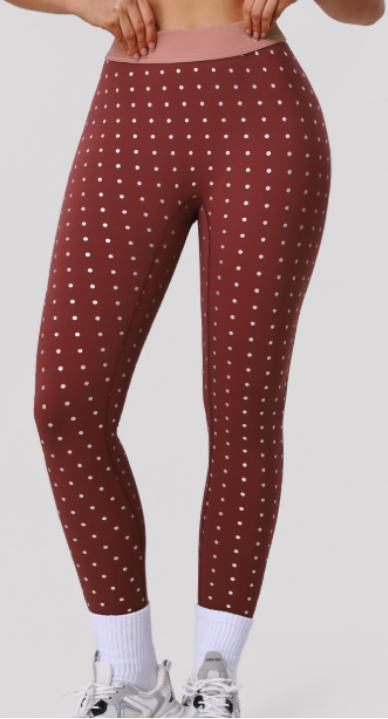 Person wearing maroon leggings with white heart pattern on a plain background