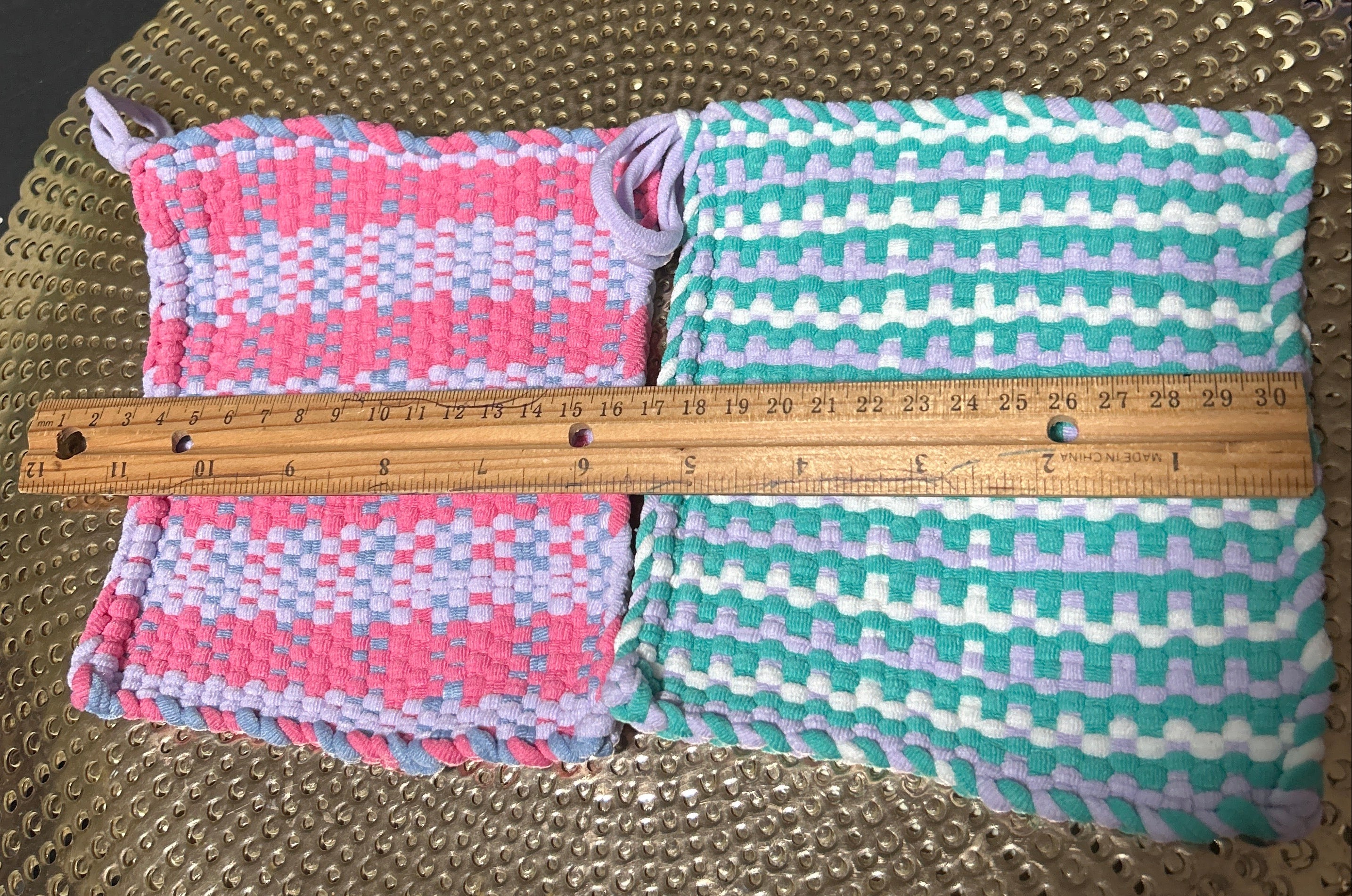 Two folded fabric swatches with a ruler on a textured surface