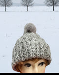Mannequin head wearing a gray knitted beanie with a blurred background