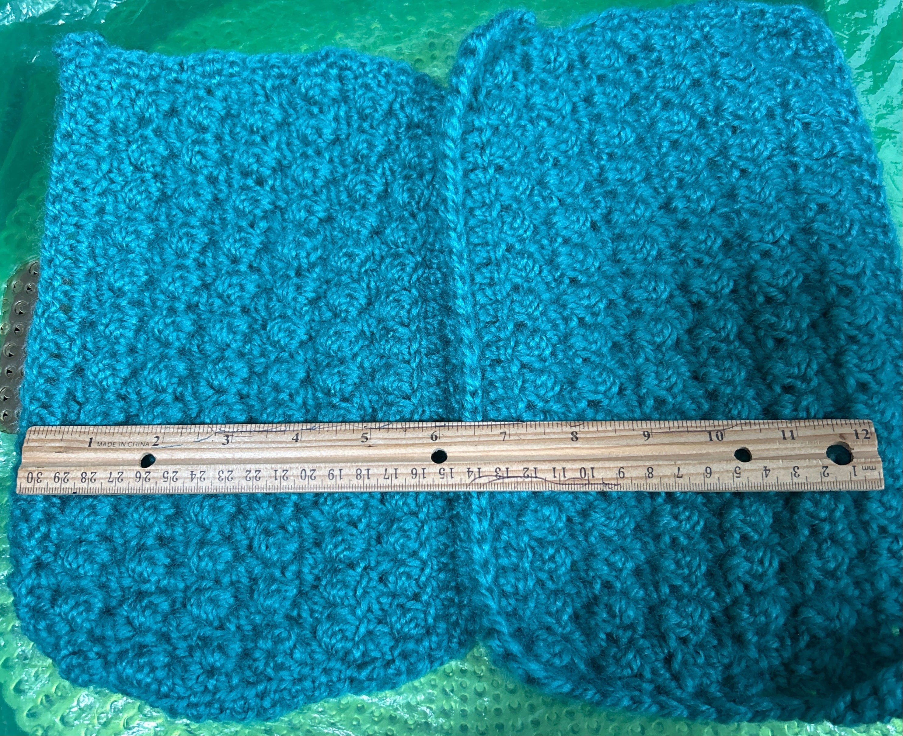 Blue knitted fabric with a ruler for scale on a green surface