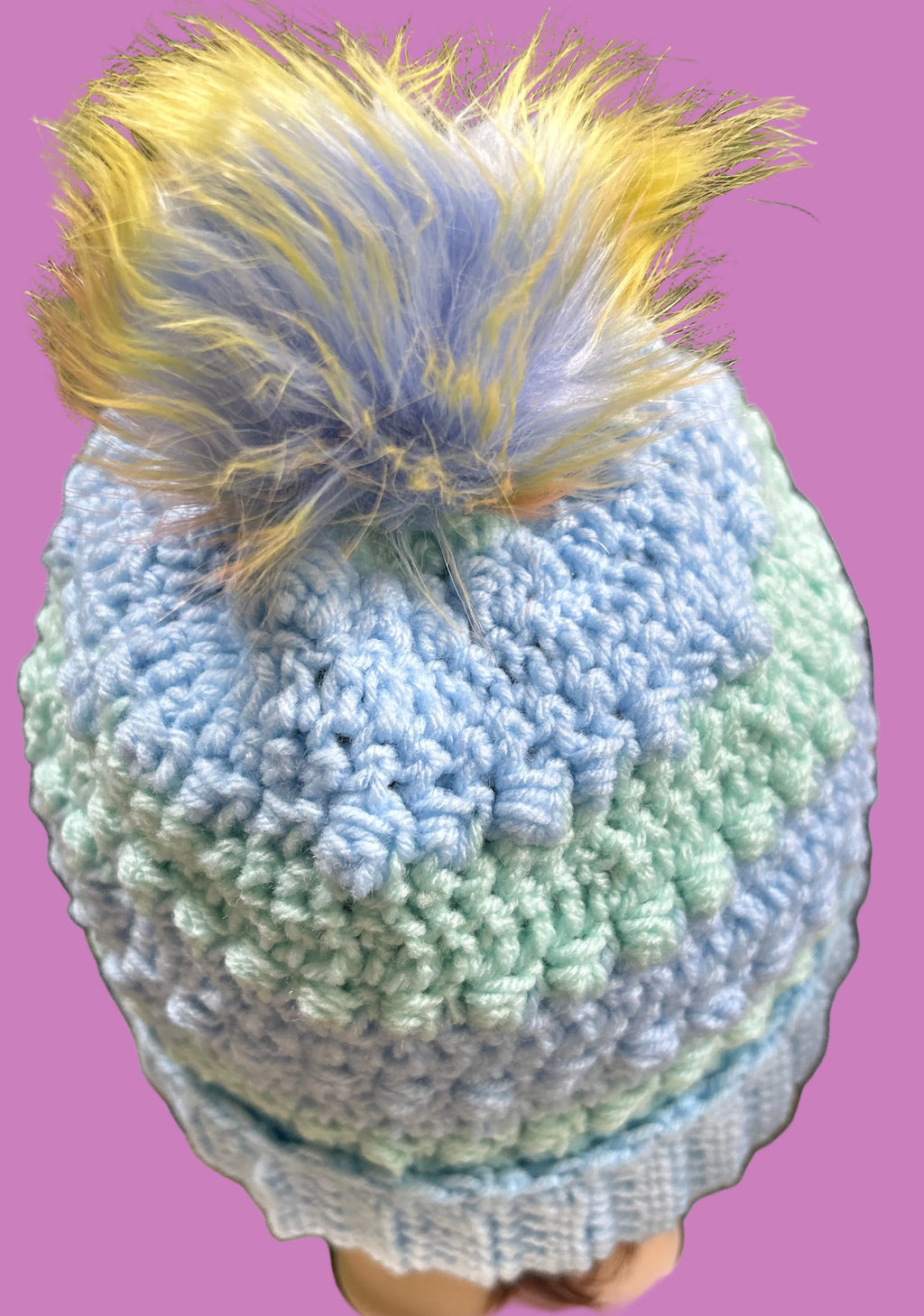 Knitted hat with a colorful pom-pom on a mannequin head.