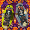 Decorative keychains with skull and floral designs on a pink surface