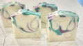 Five small soap bars with a marbled design on a marble surface.