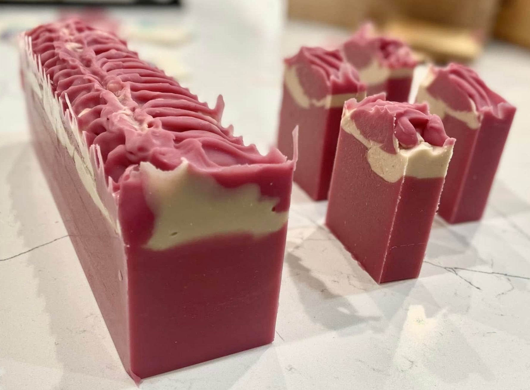 Pink and white soap bars on a marble surface