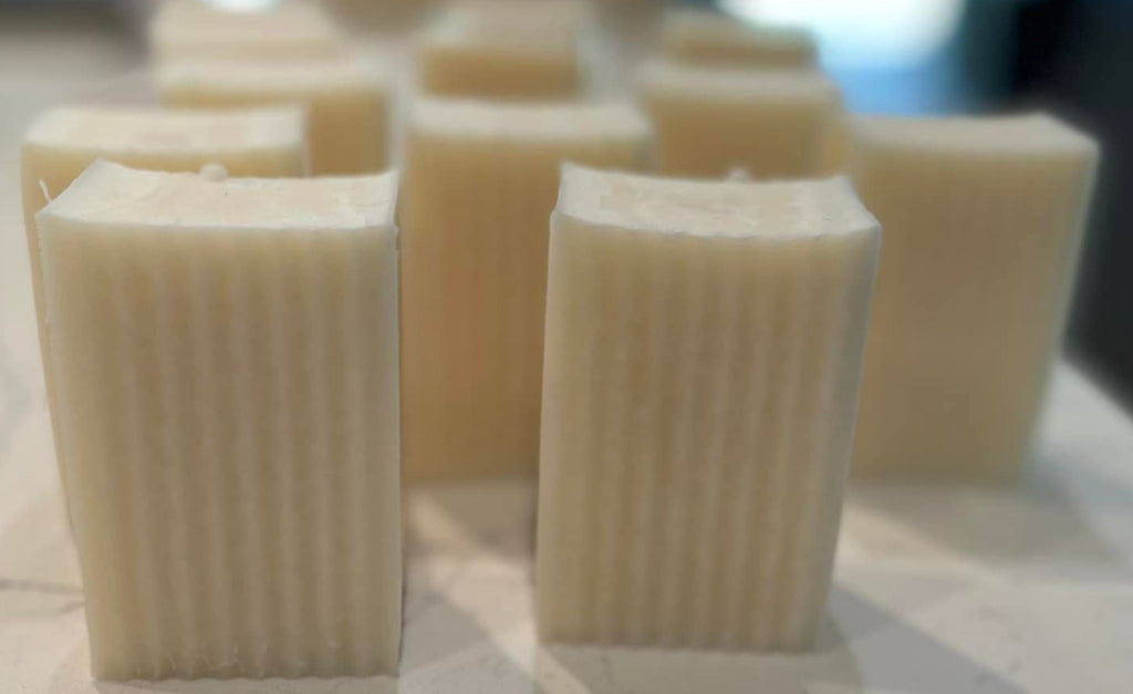 Row of square soap bars on a textured surface with a blurred background