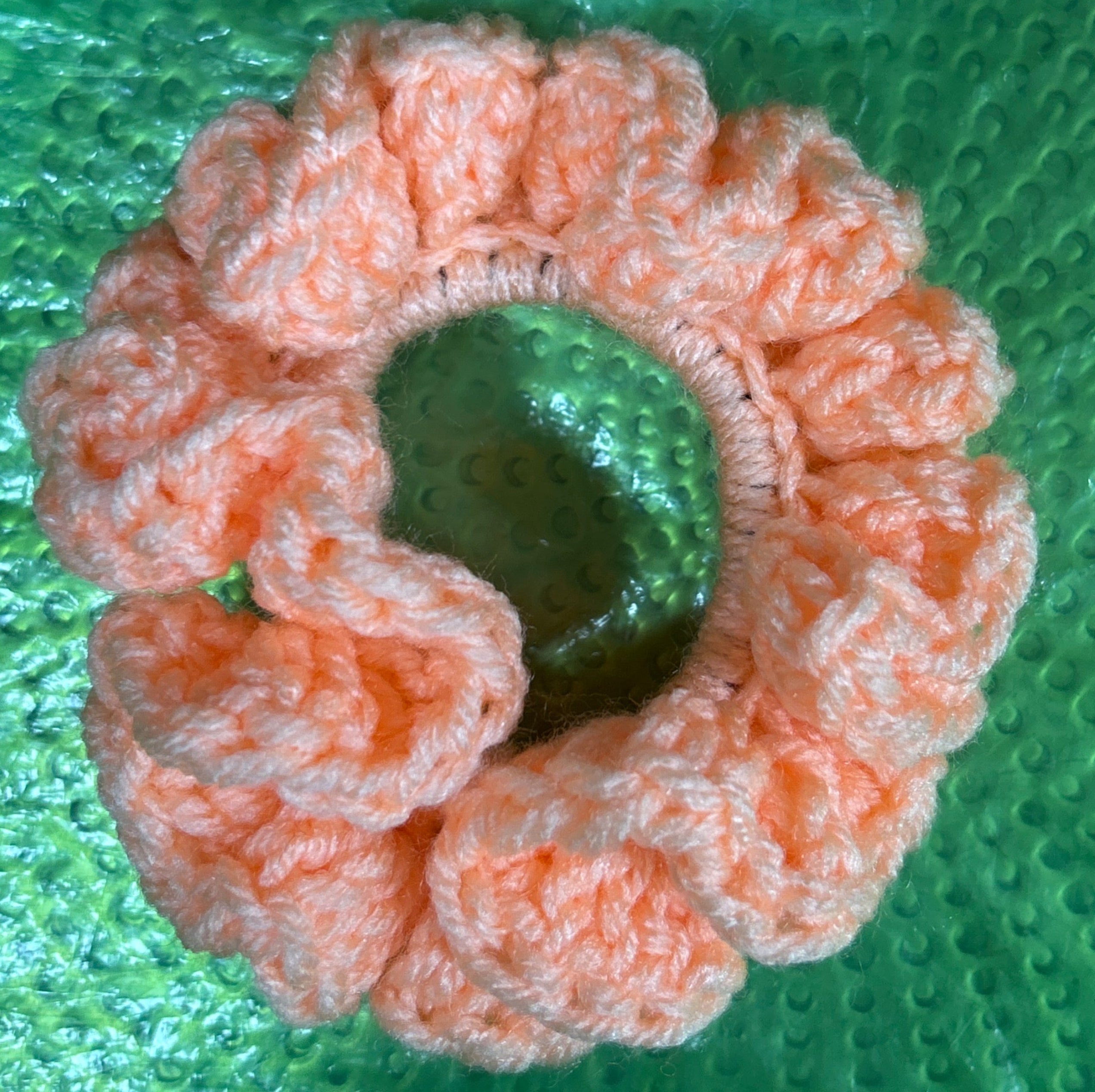Pink scrunchie on a green textured surface