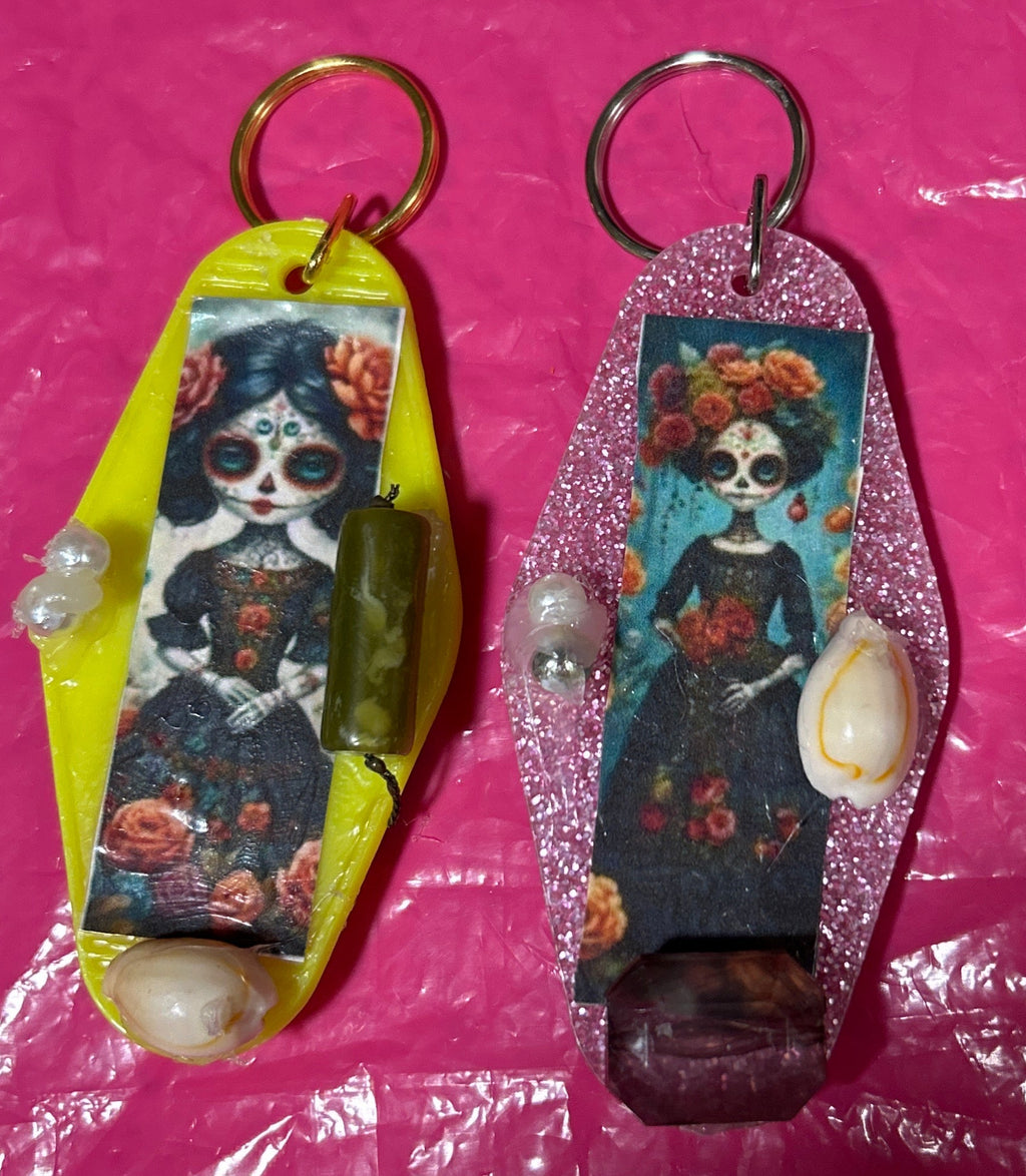 Two keychains with artistic designs on a pink surface
