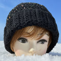 Mannequin head wearing a black knitted hat with a blurred background