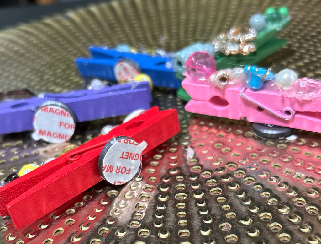 Colorful clothespins attached to a pegboard with various decorative items.