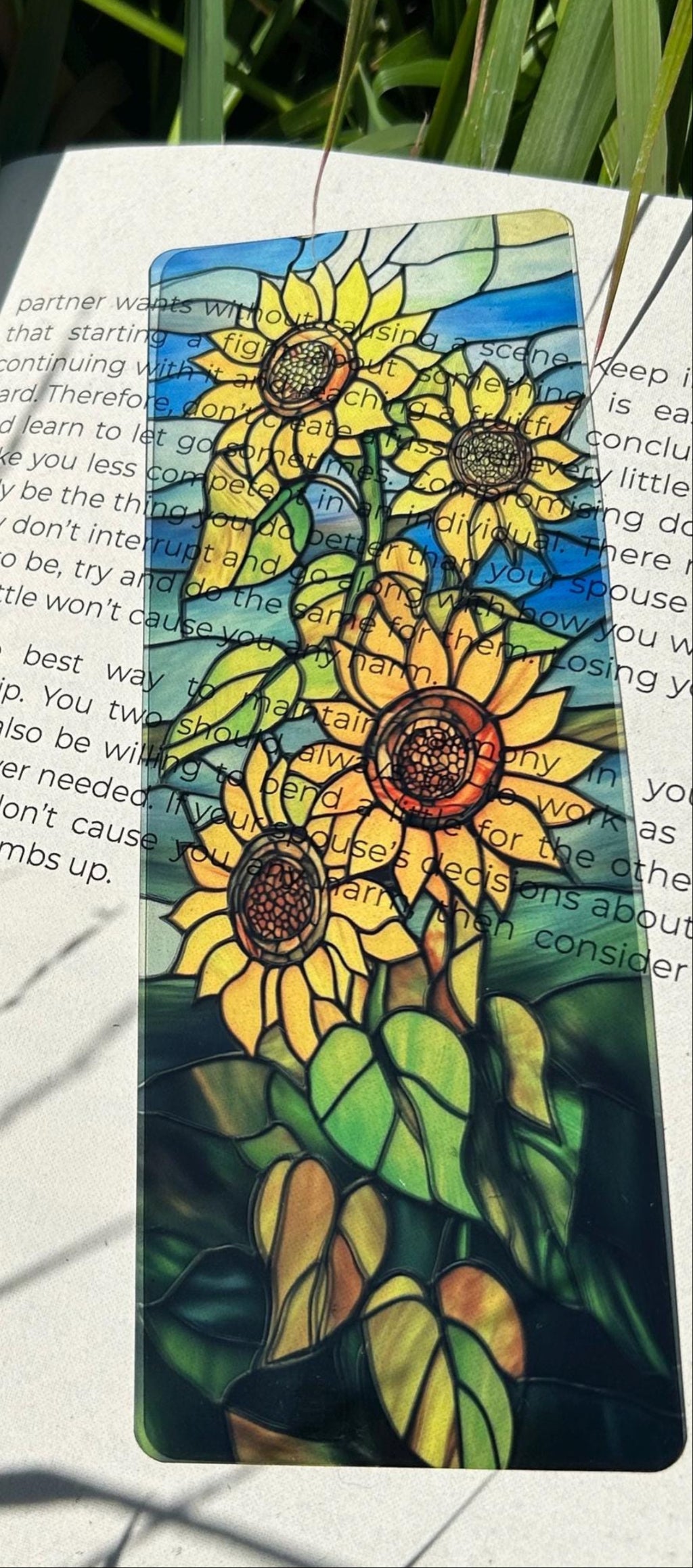 Sunflower-themed bookmark on an open book with greenery in the background