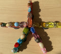 Colorful beaded cross on a pink plastic surface