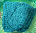 Teal knitted item on a green textured surface