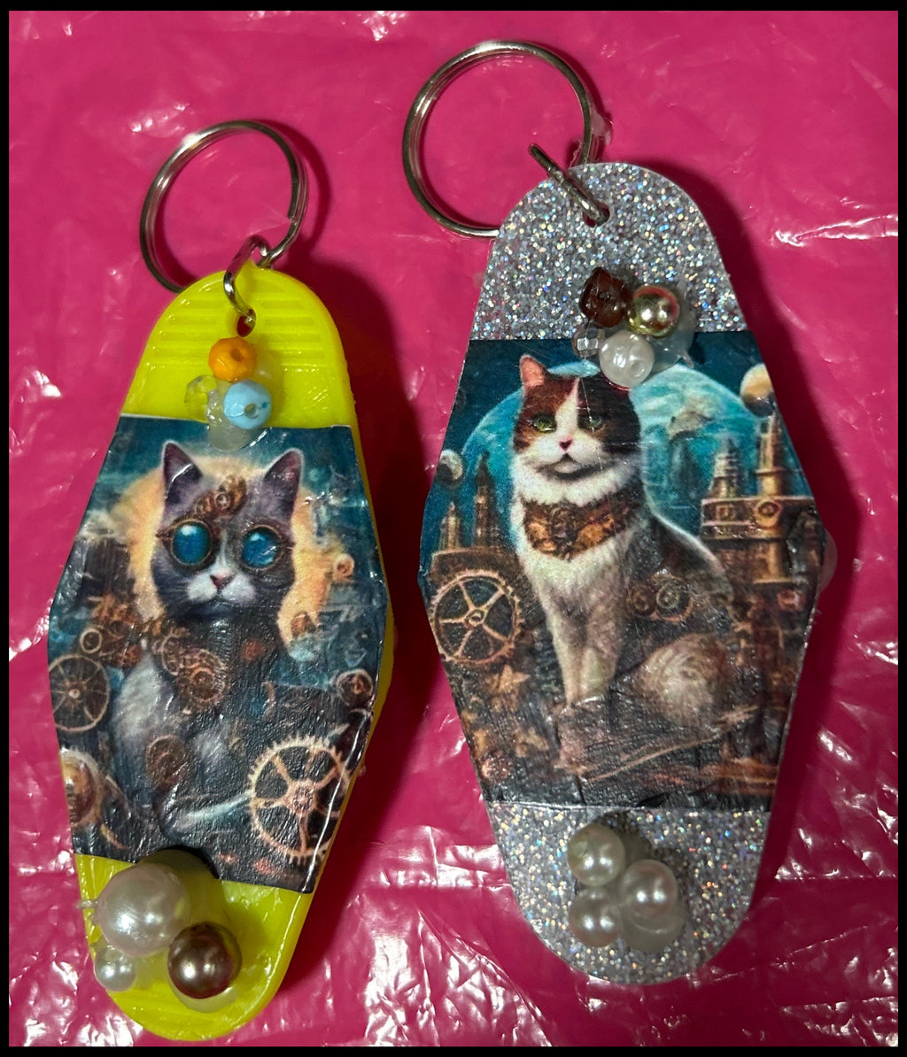 Two keychains with cat designs on a pink surface