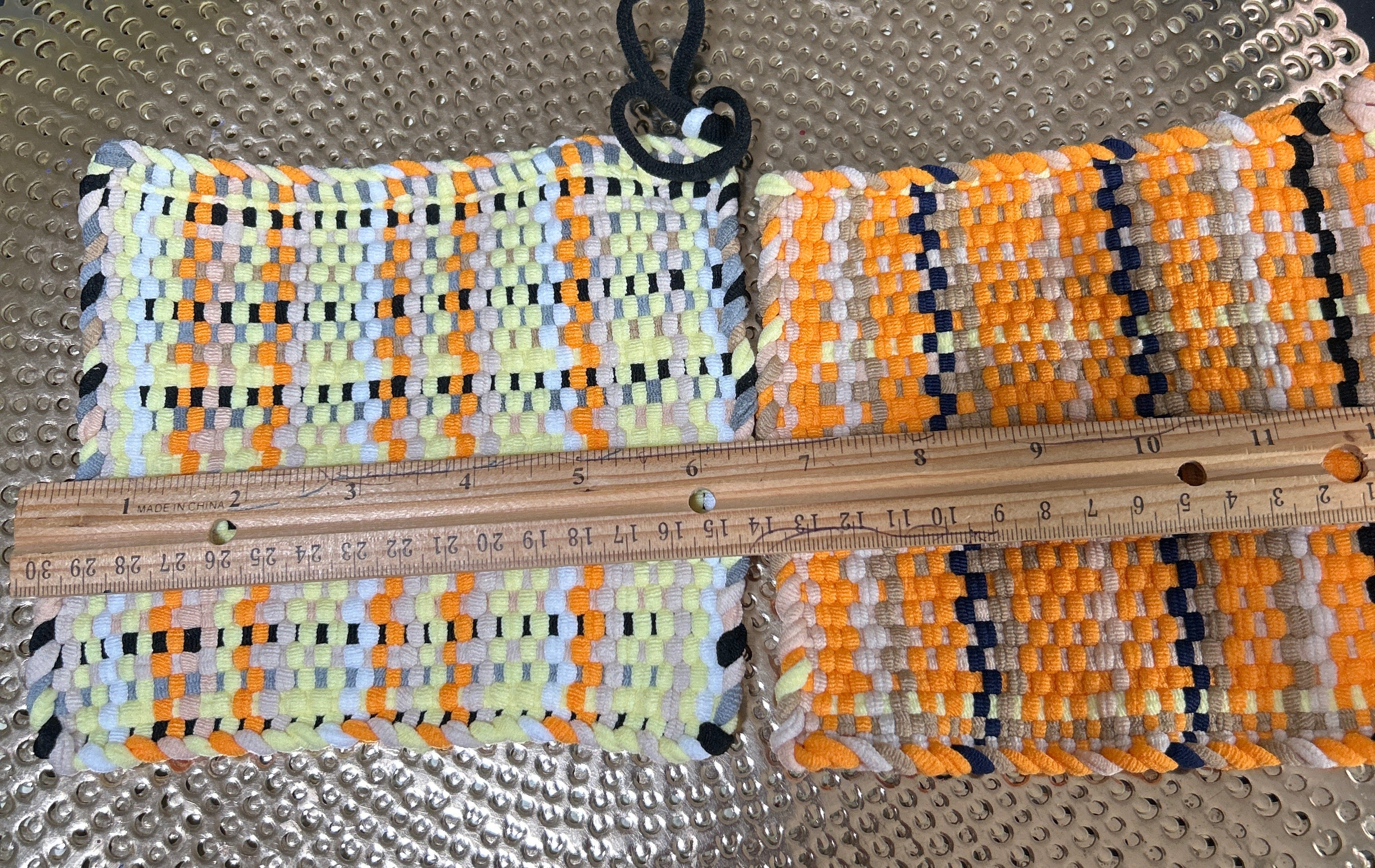 Colorful woven belt with a ruler for scale on a textured surface