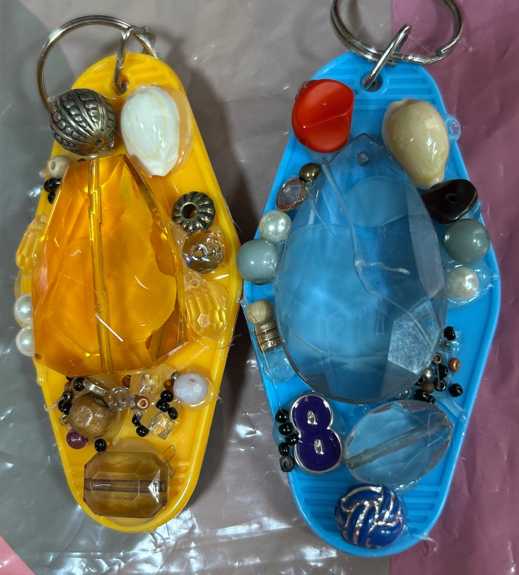 Two small boats filled with jewelry on a reflective surface.