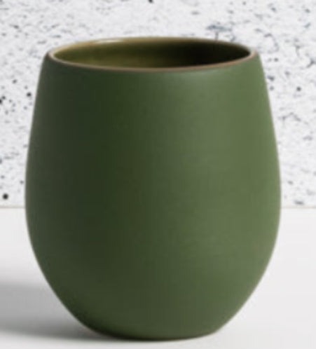 Green ceramic cup on a light gray surface with a textured white background