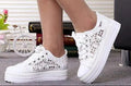 White lace-up sneakers worn by a person with a blurred indoor background