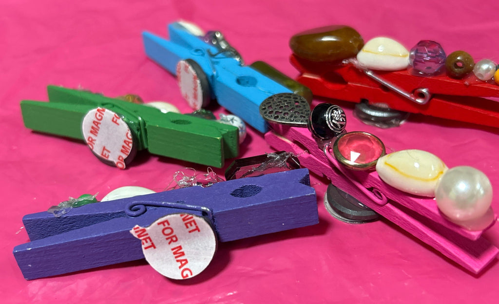 Colorful clothespins with decorative elements on a pink background