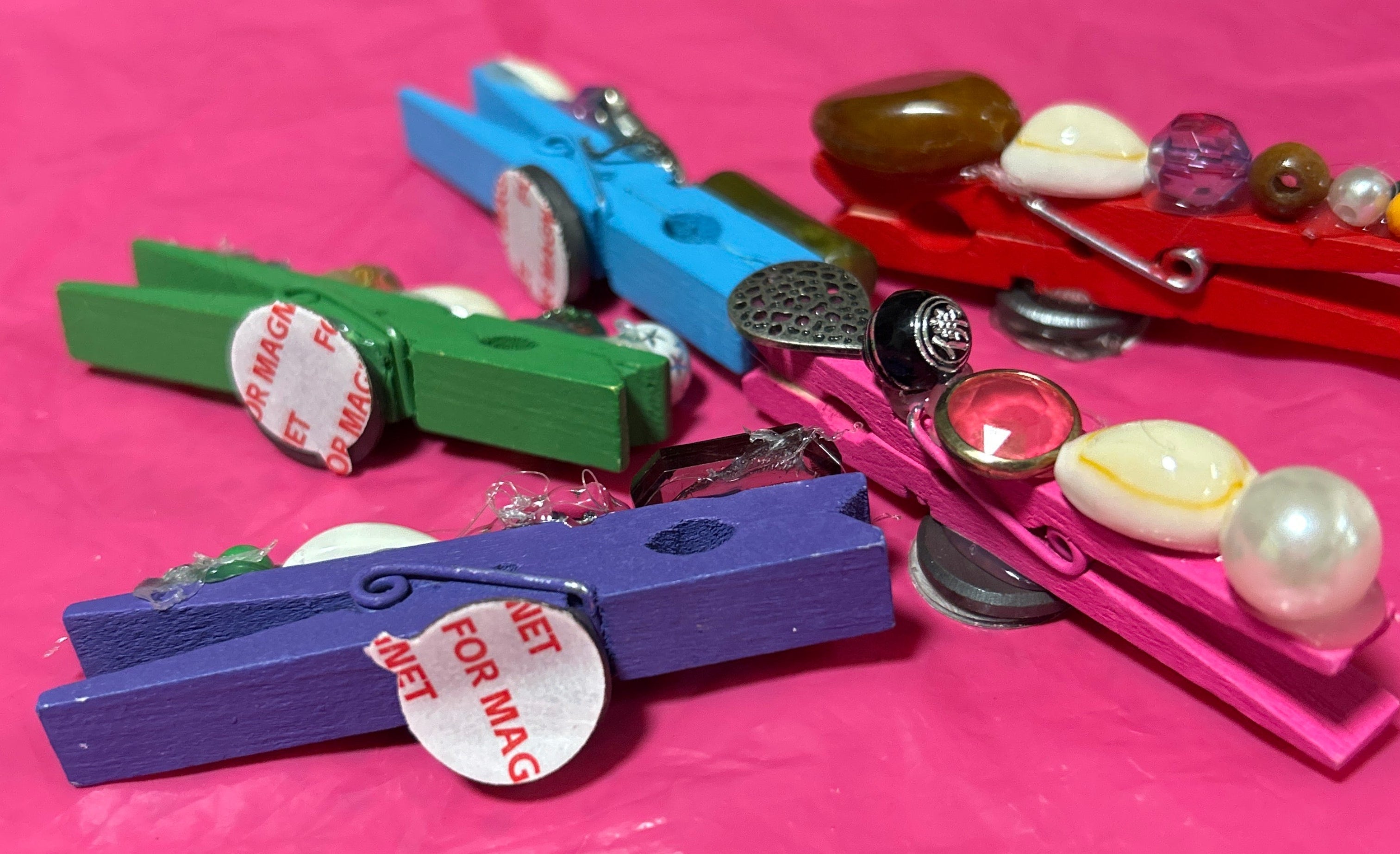 Colorful clothespins with decorative elements on a pink background