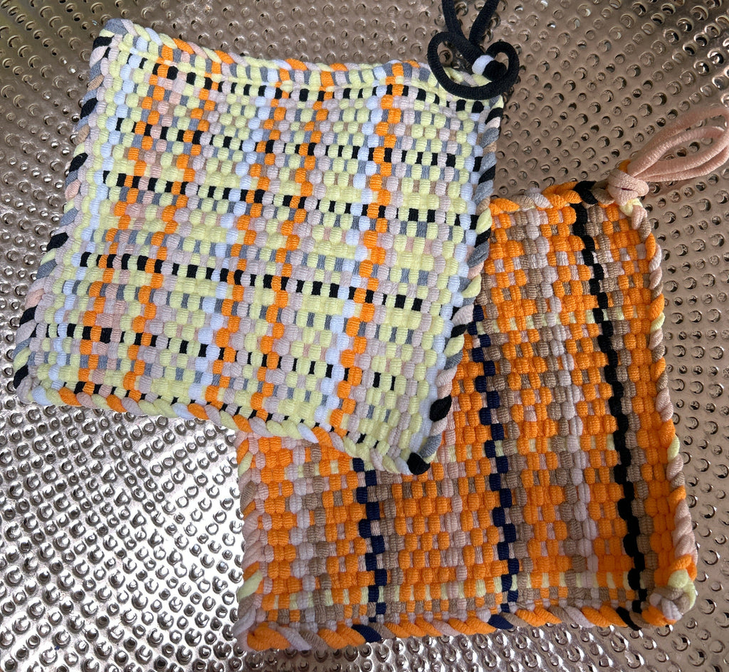 Two woven pouches, one multicolored and one with black stripes, on a textured surface.