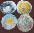 Four multicolored scrubbies on a textured gold surface