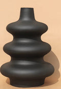 Black ceramic vase with a unique design on a beige background
