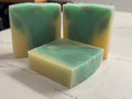 Three green and yellow soap bars on a marble surface with a blurred background