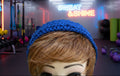 Mannequin head with a blue knitted headband on a green surface