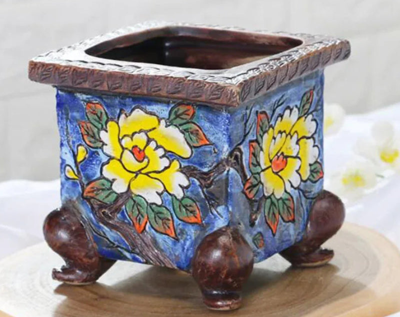 Decorative ceramic planter with floral design on a white background