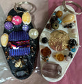 Two decorative keychains with colorful beads and stones on a pink and gray background