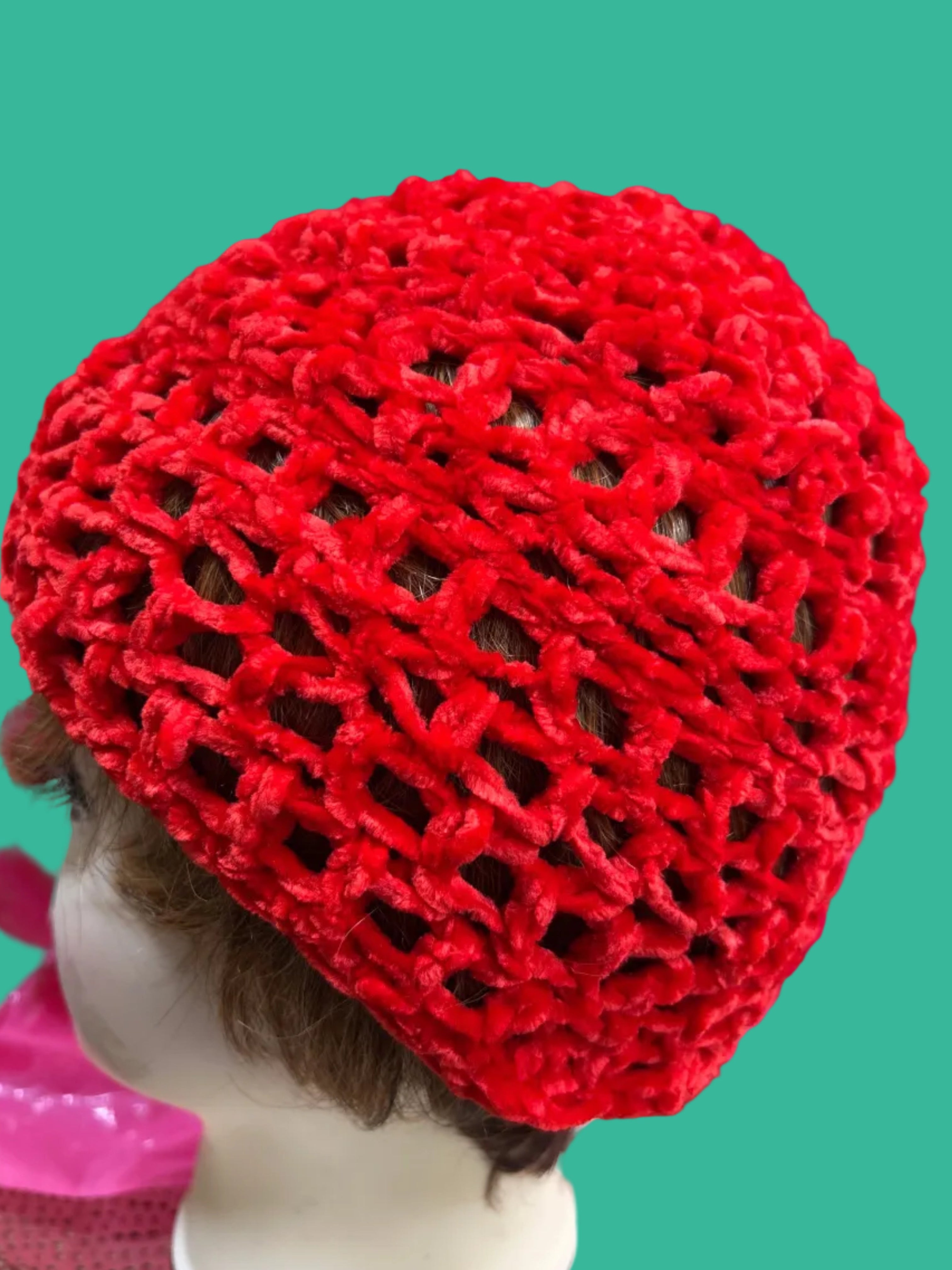 Red knitted hat on a mannequin head with a pink background