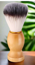Shaving brush with wooden handle on a reflective surface