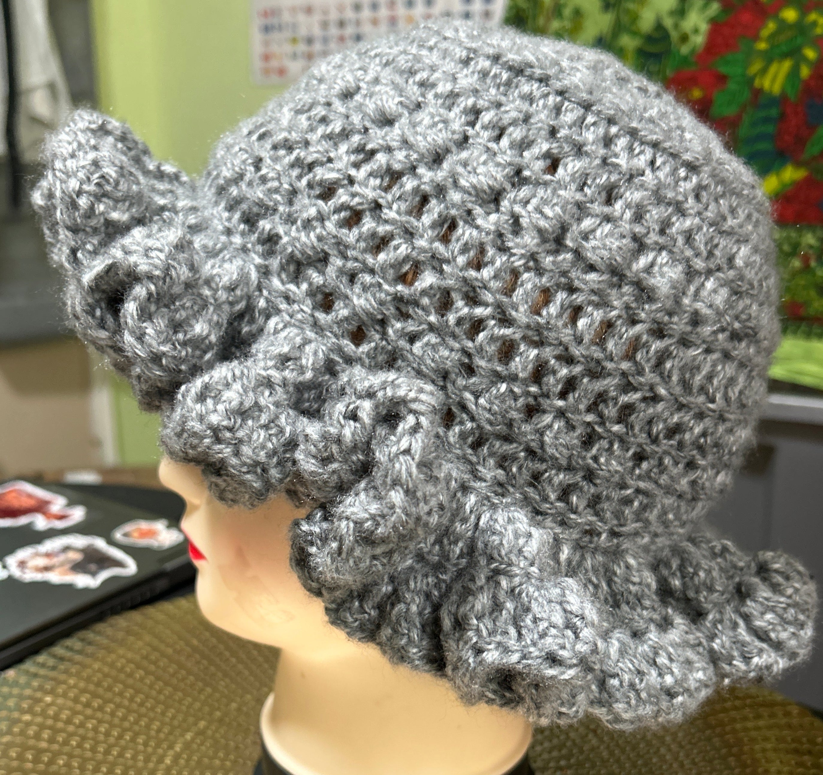 Silver crochet hat on a mannequin head against a colorful background