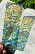 Colorful ship-themed bookmark on an open book with greenery in the background