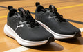 Black Puma sneakers with white soles on a white background