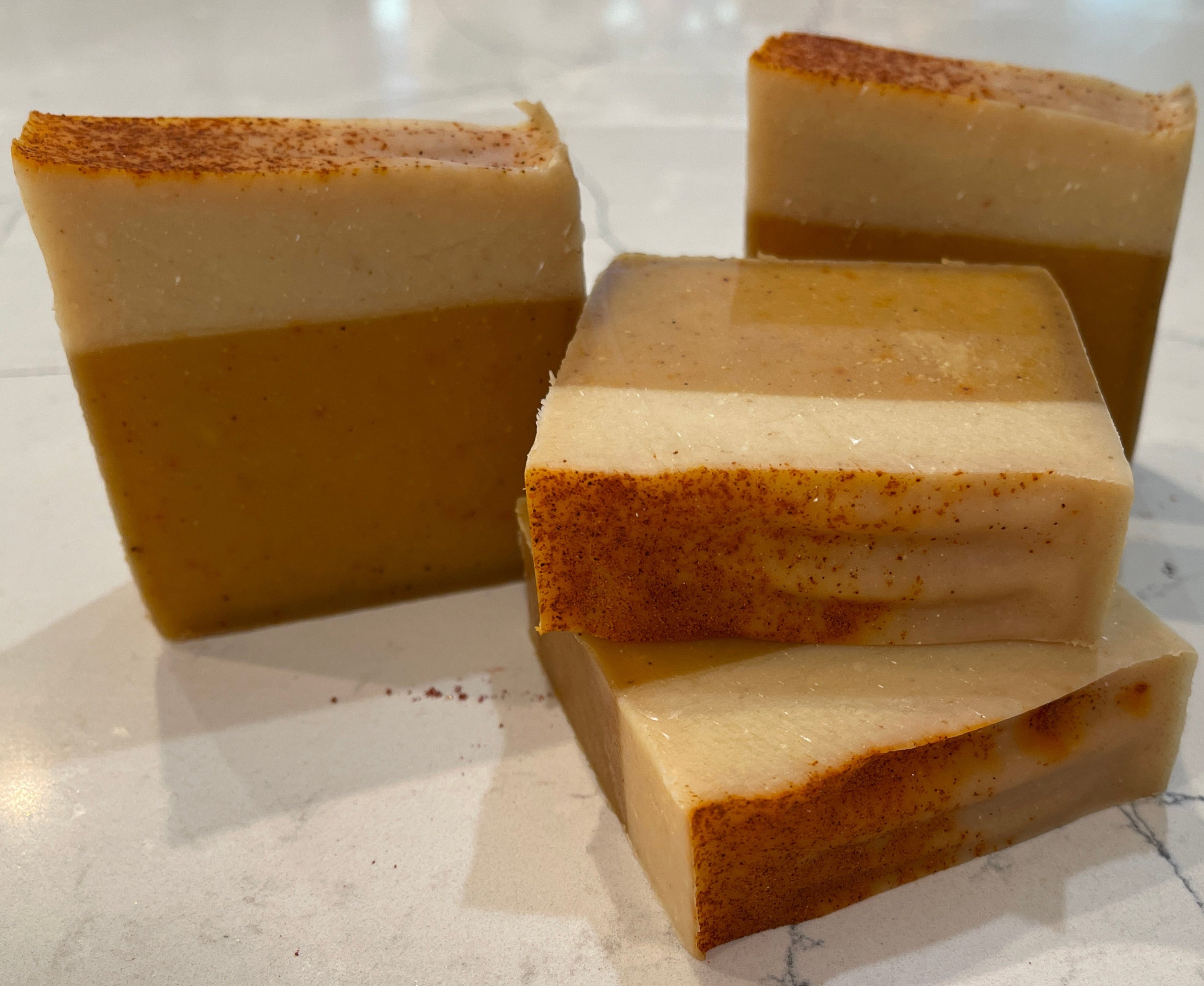 Three bars of soap stacked on a marble surface