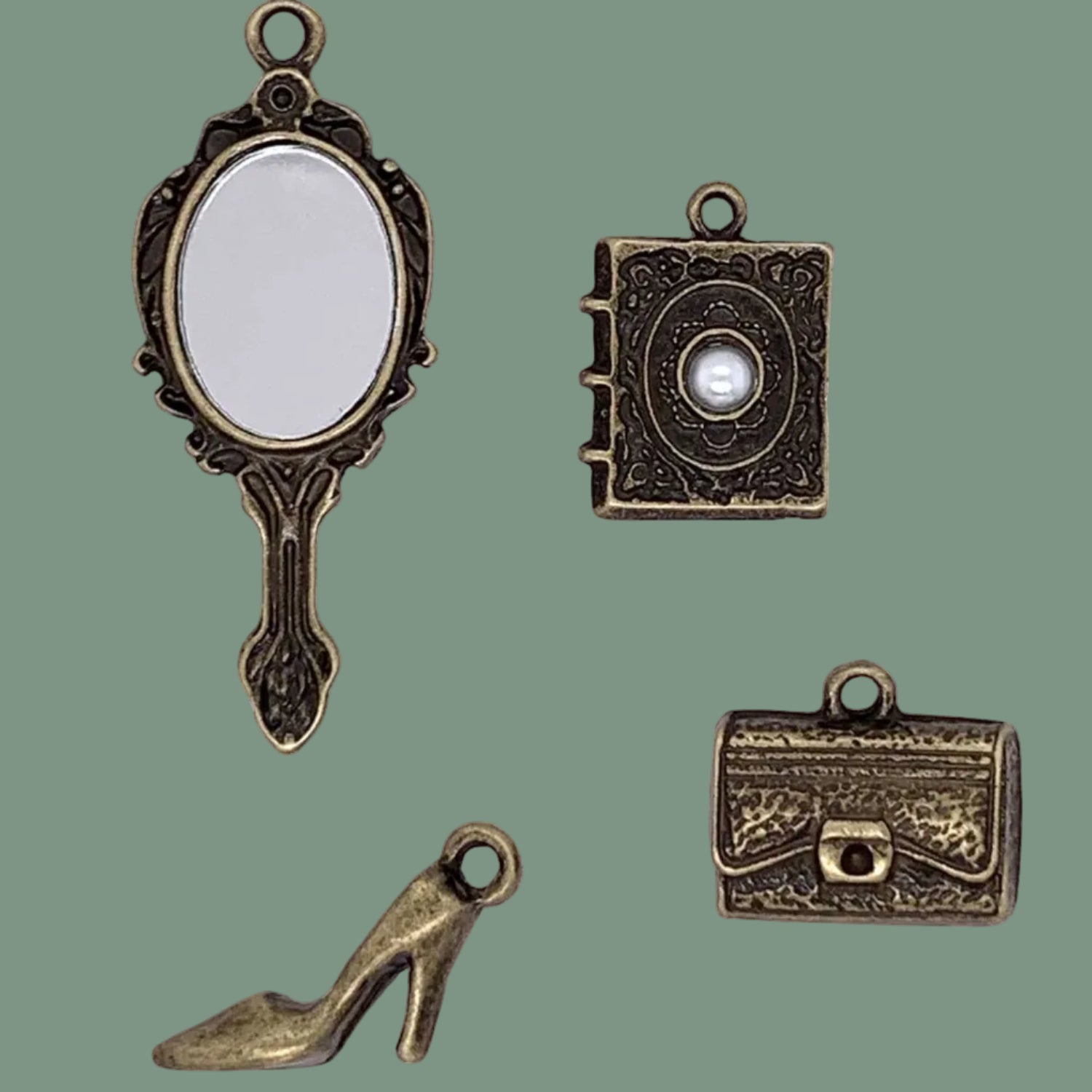 Set of four vintage-style bronze charms including a mirror, book, high heel shoe, and suitcase on a white background.