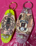 Two decorative keychains with intricate designs on a pink surface