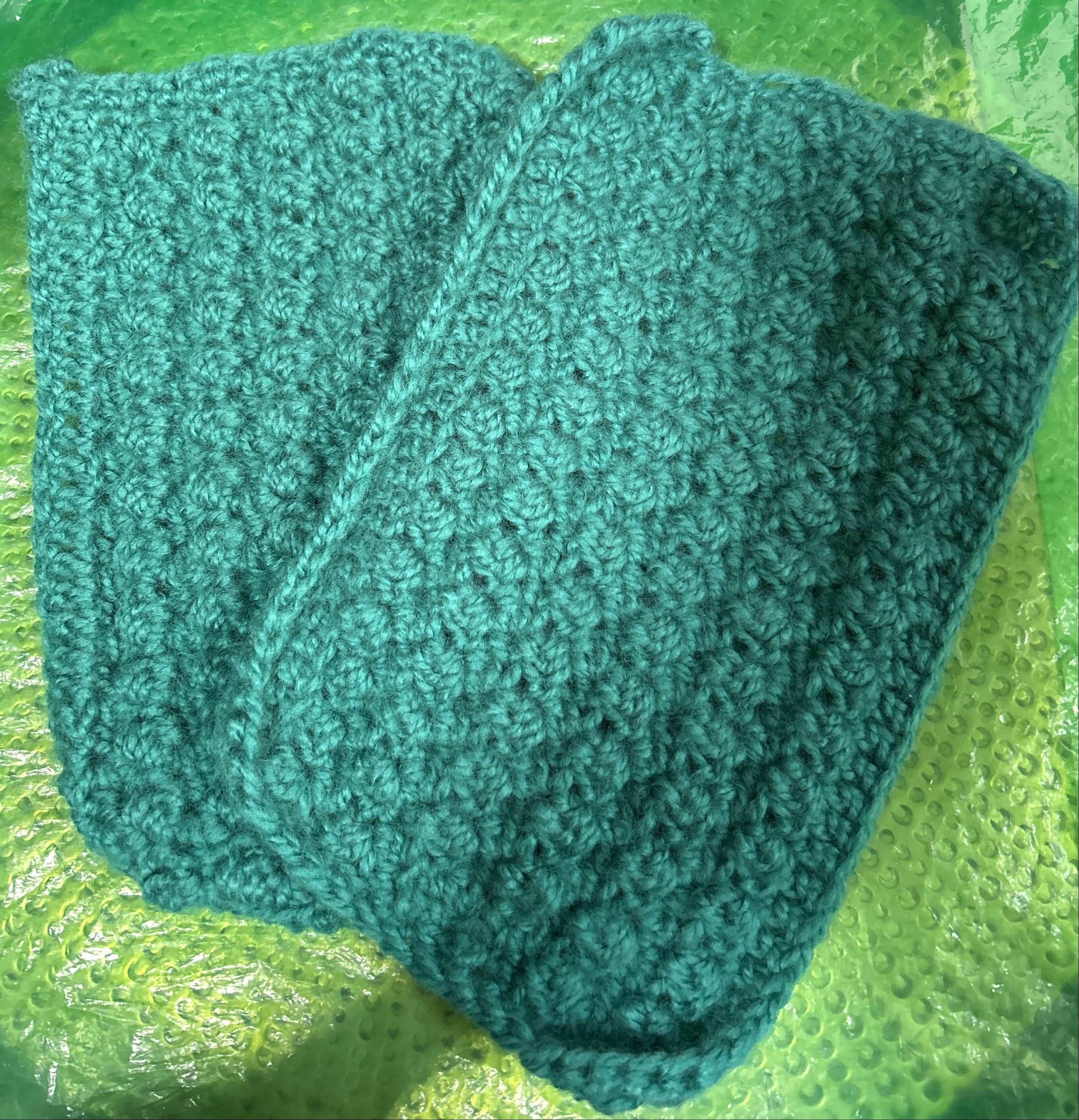 Green knitted fabric on a green textured surface