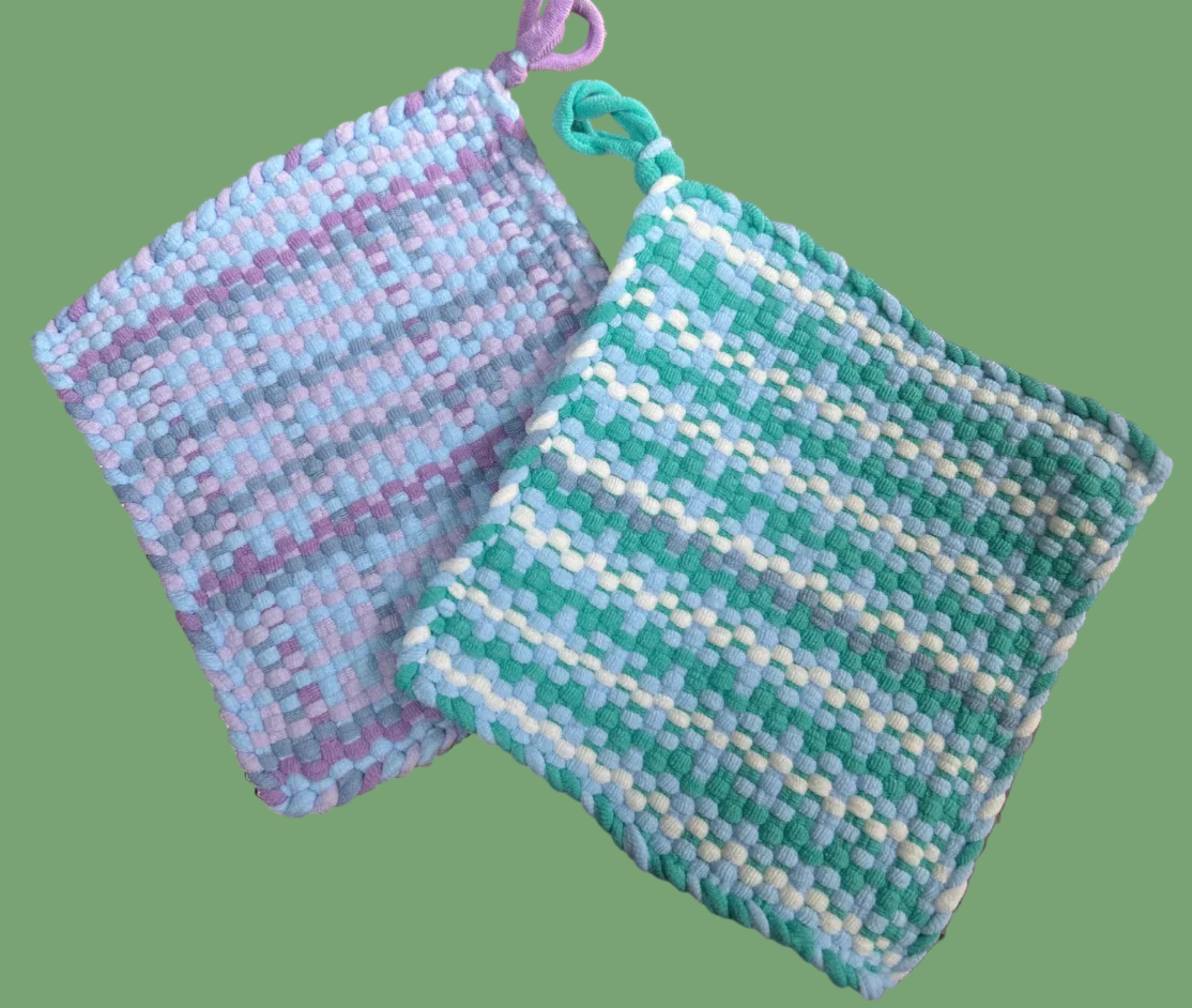 Two woven potholders, one purple and one green with white, on a green background.