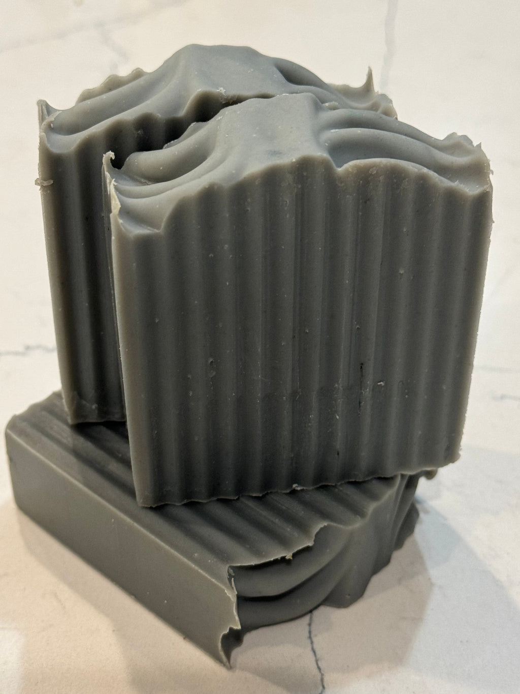 Gray soap bar with decorative design on a light marble background