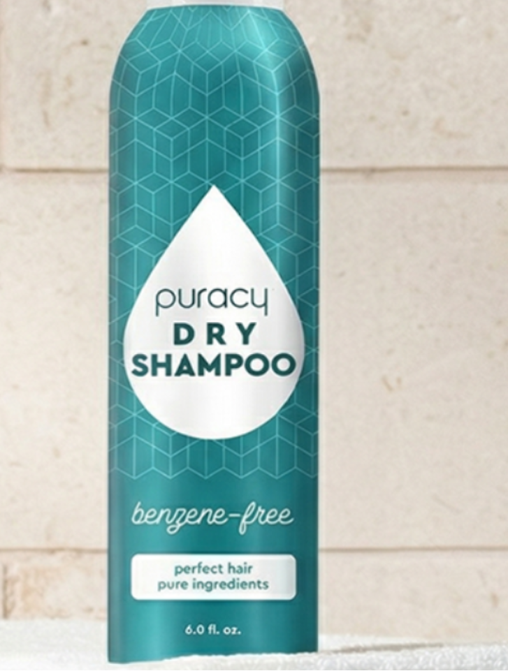 Puracy dry shampoo bottle on a towel with a tiled wall background