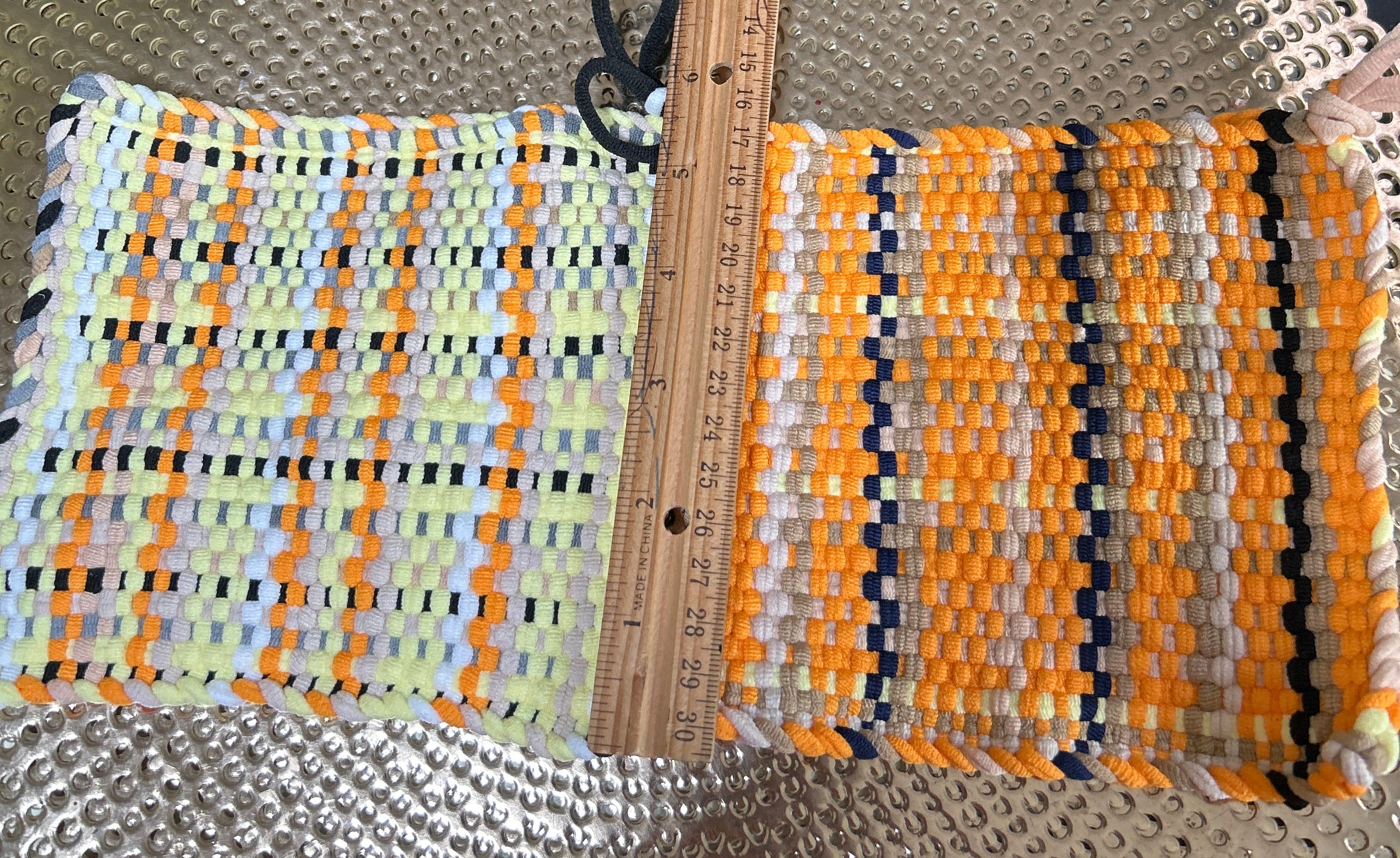 Colorful woven mat with a ruler for scale on a textured surface