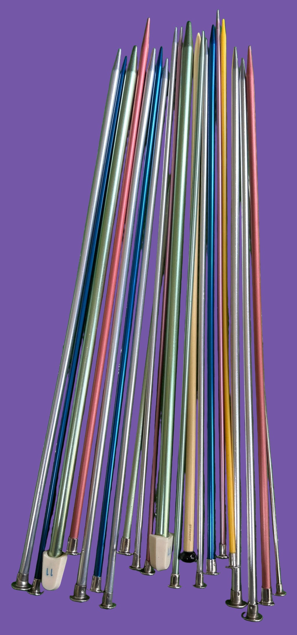 Set of colorful knitting needles on a green textured surface