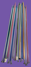 Set of colorful knitting needles on a green textured surface