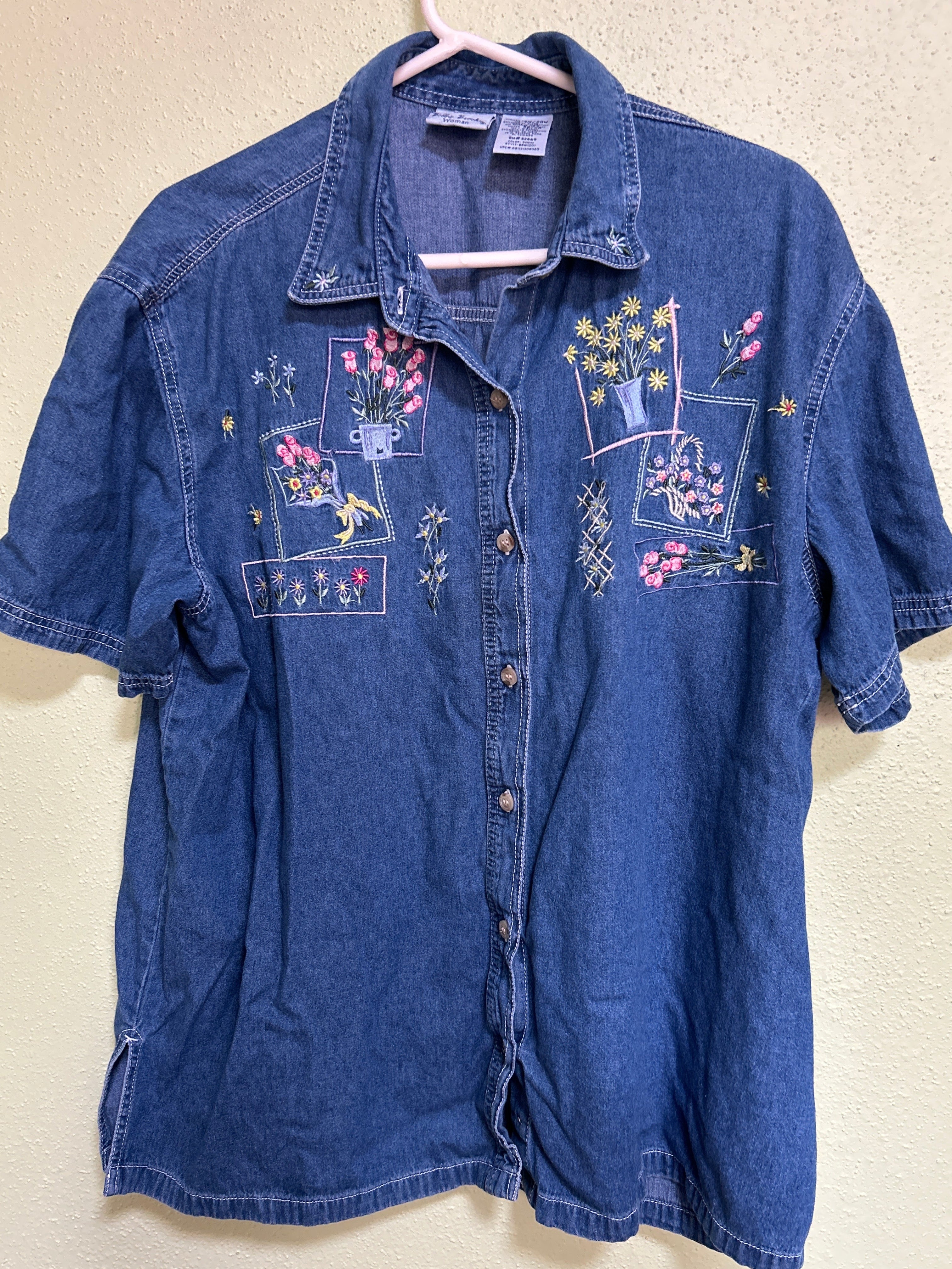Folded blue denim jacket with embroidered designs on a beige background