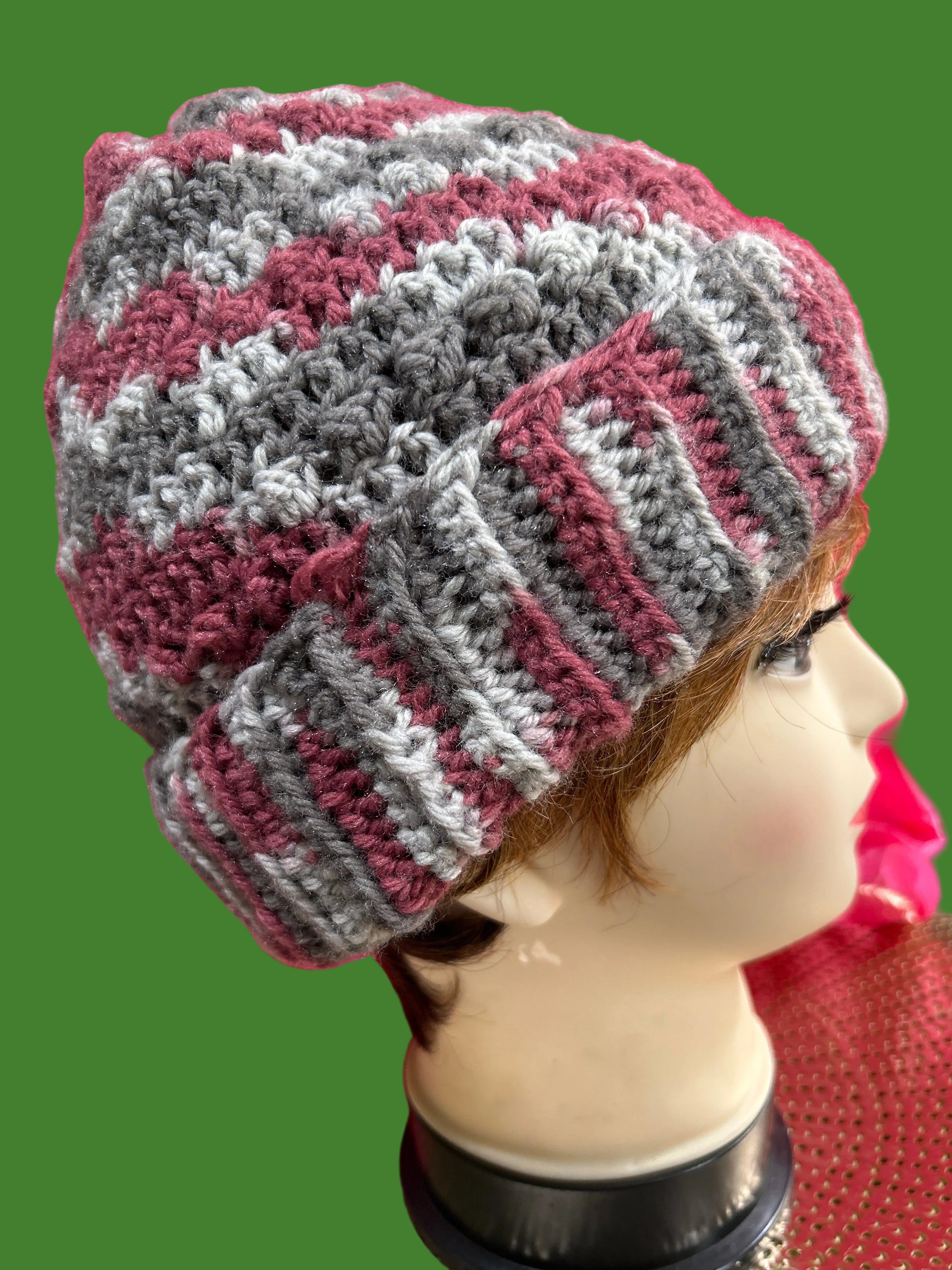 Mannequin wearing a striped knitted hat with a pink background