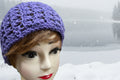 Mannequin head wearing a purple knitted hat on a green background