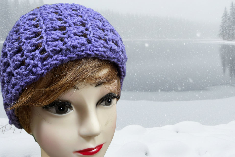 Mannequin head wearing a purple knitted hat on a green background